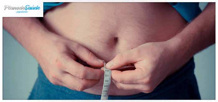 homem segurando fita métrica próximo à barriga - Cirurgia de Redução do Estômago