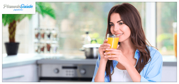 Mulher sorrindo e bebendo suco de laranja - sistema imunológico