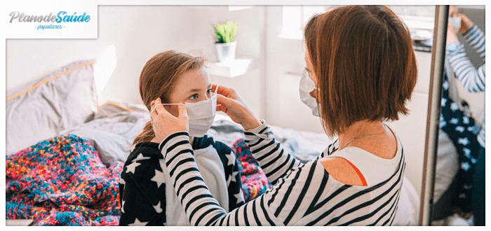 Mulher colocando máscara na filha - coronavírus